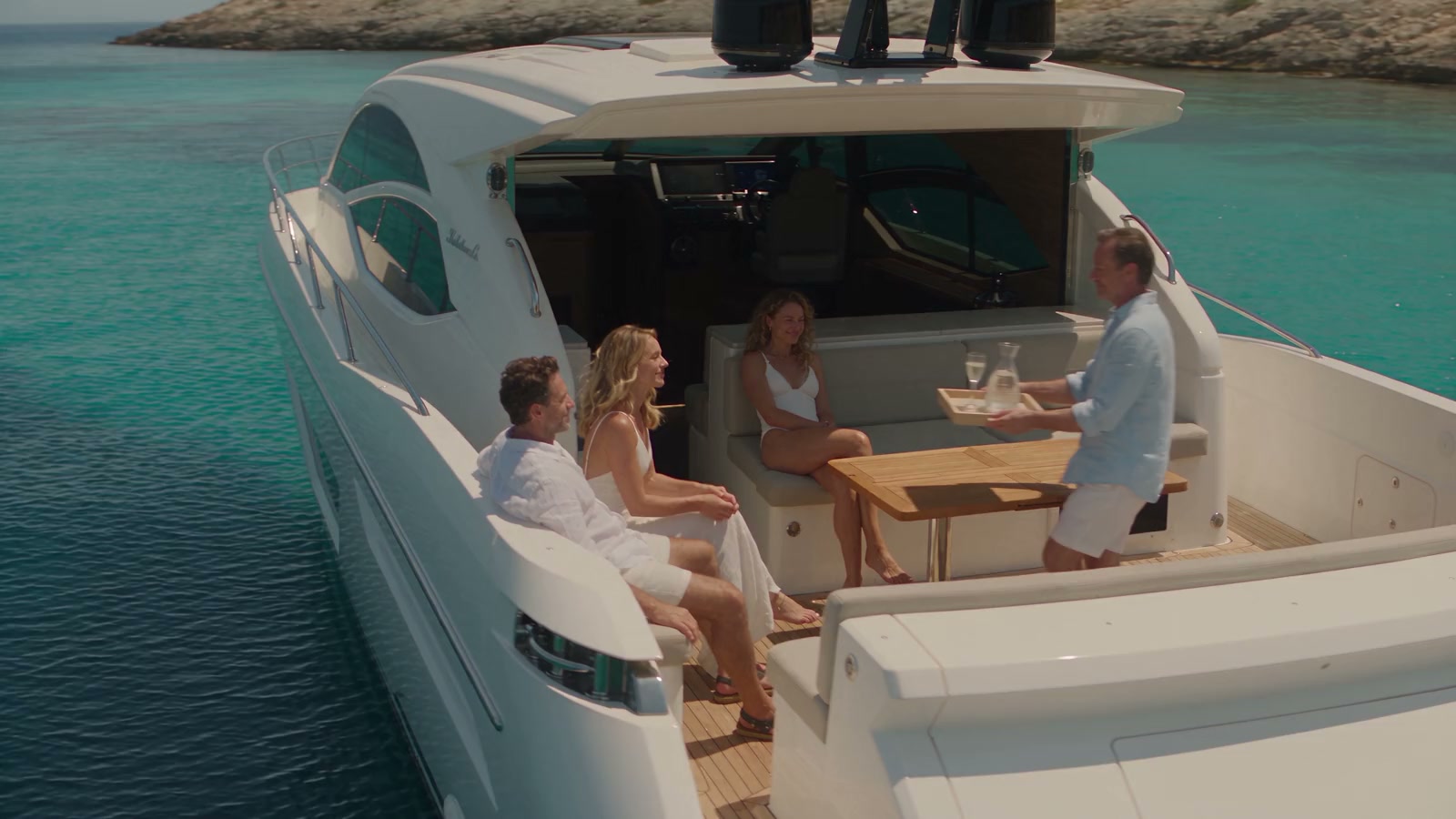 Friends sharing an afternoon aboard a yacht in a sheltered turquoise bay